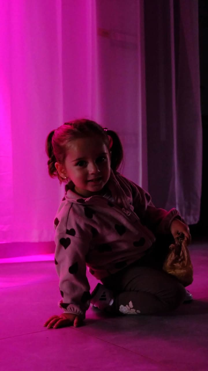 O fetiță zâmbind în lumina roz