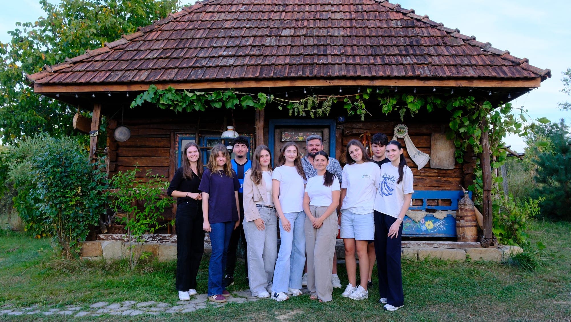 Grupul de inițiativă în fața unei case tradiționale din lemn, la Pensiunea Țara Li Pintea