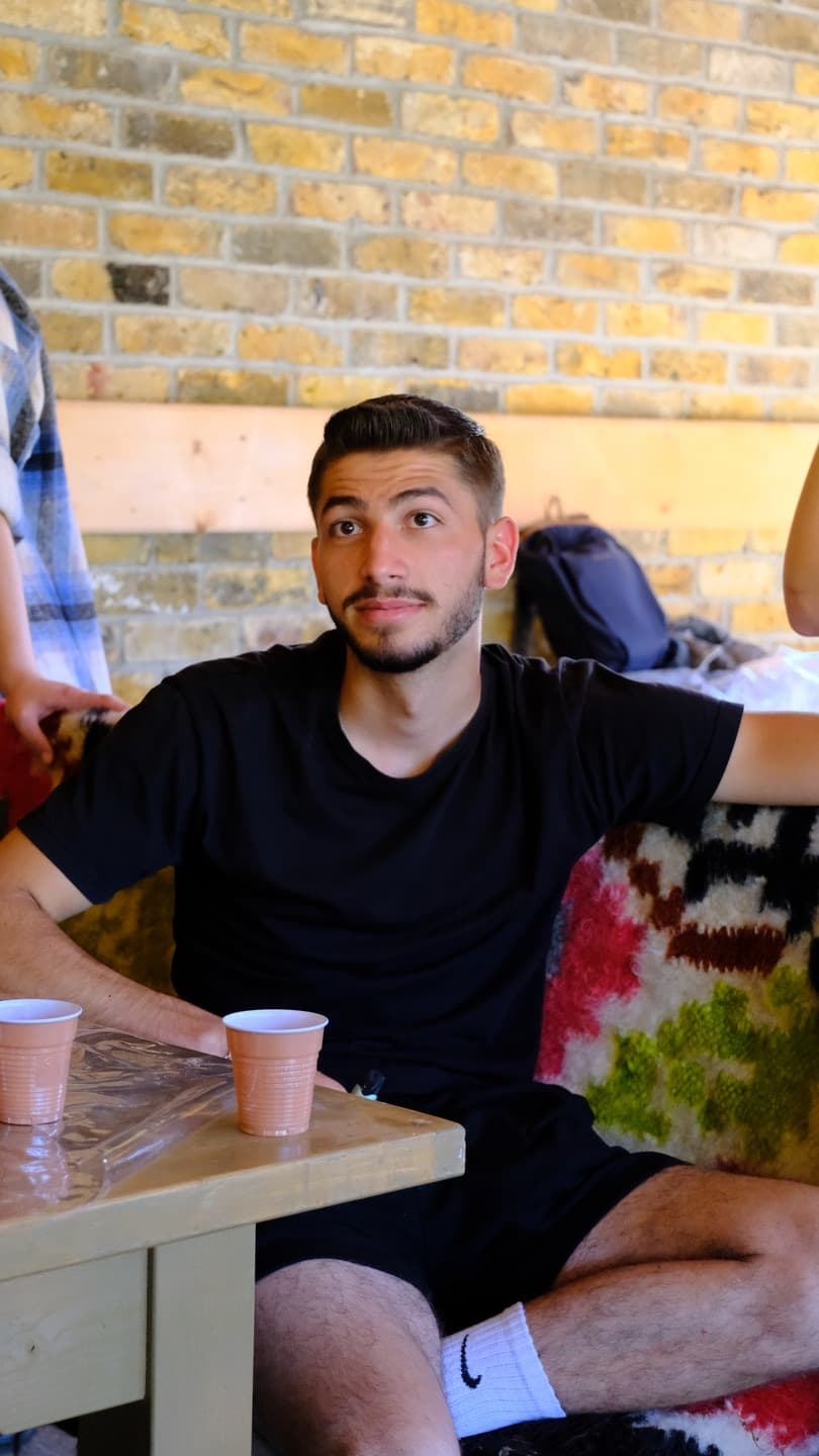 Un tânăr zâmbind, lângă un perete de cărămidă